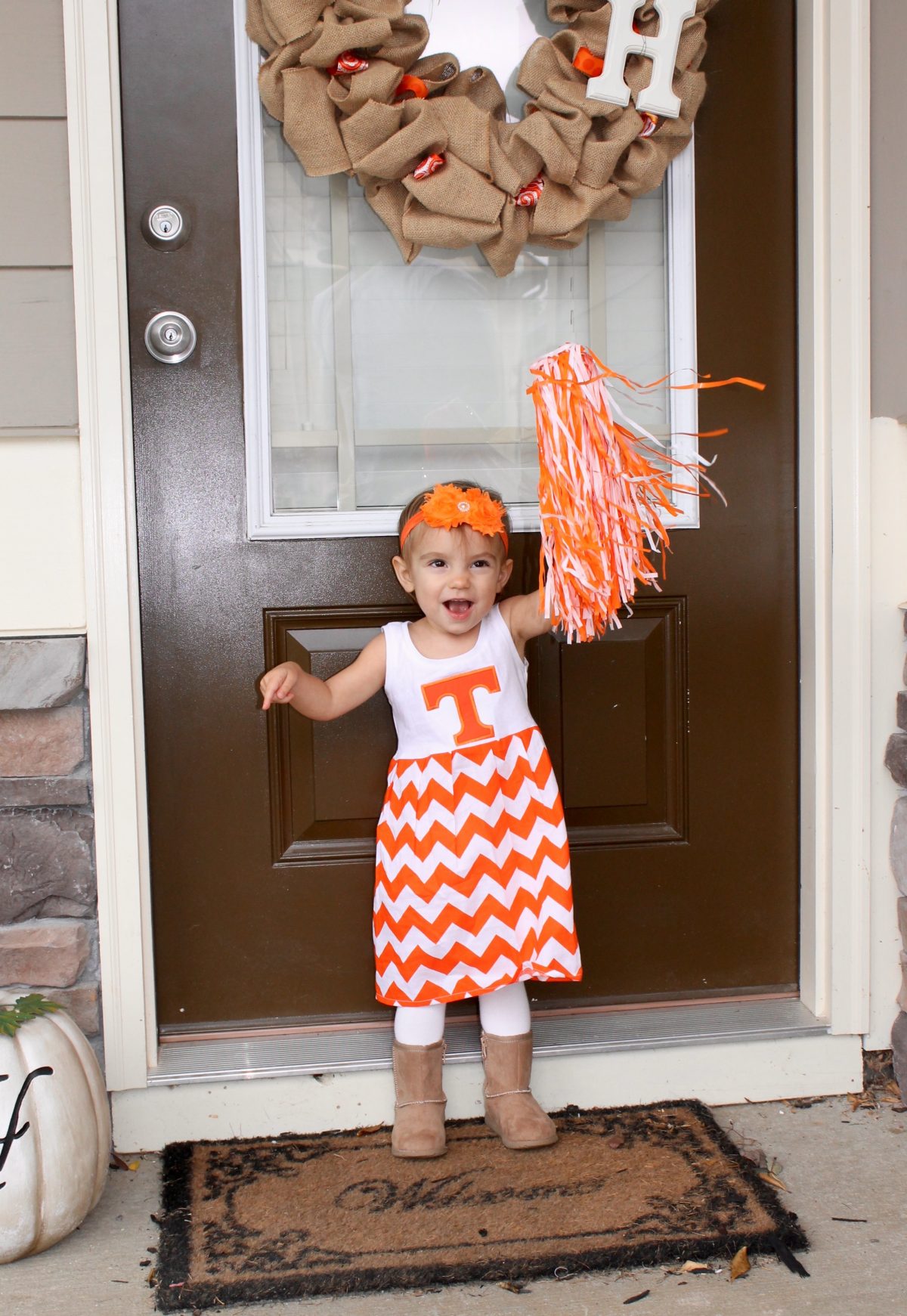 Toddler wearing University of Tennessee Dress holding Orange Pom Pom