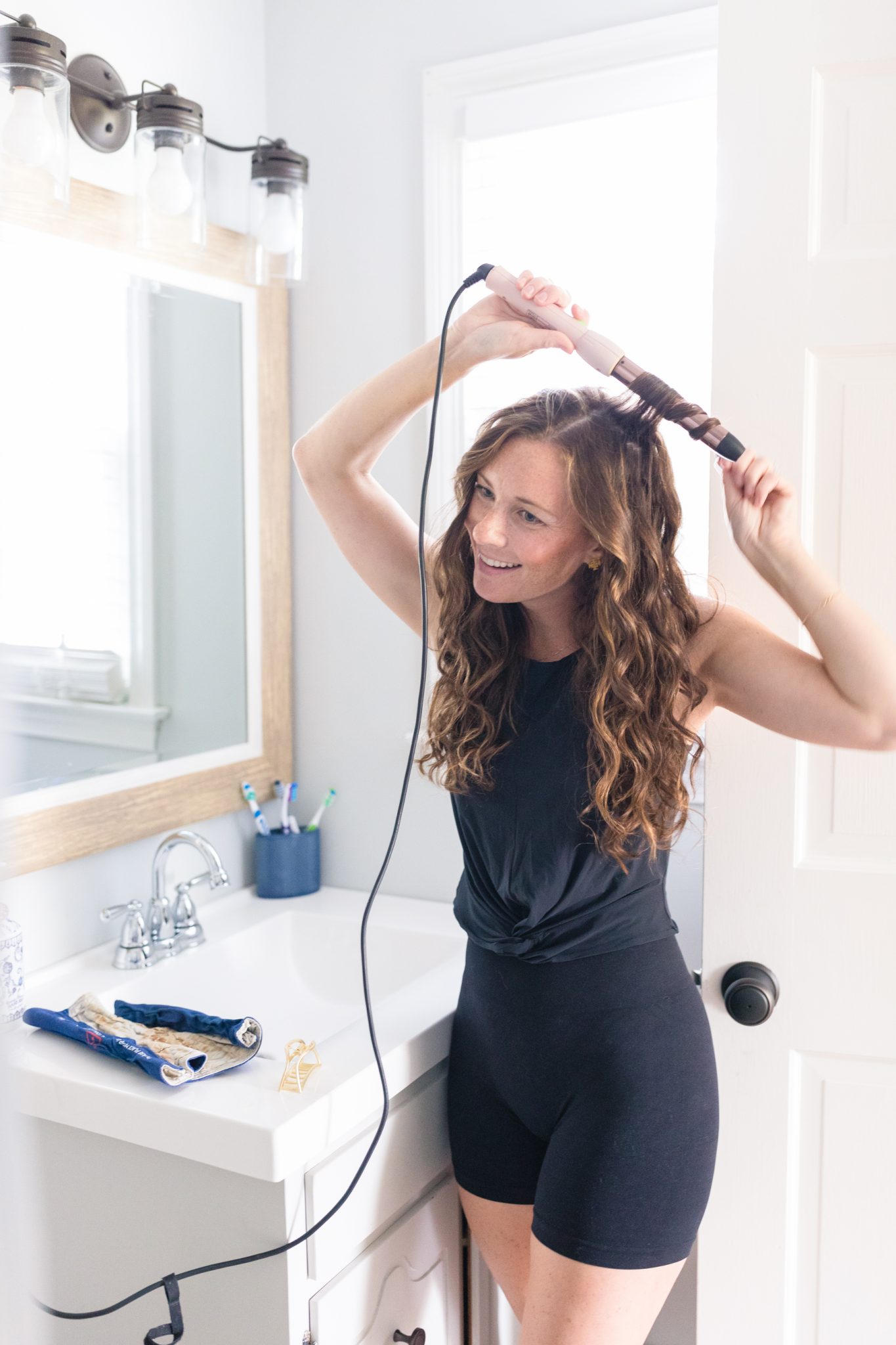 woman demonstrating how to use a curling wand