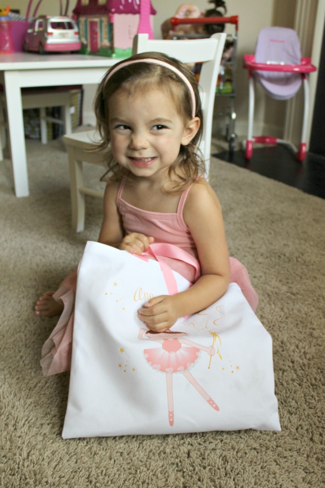 Little girl smiling holding a ballerina bag
