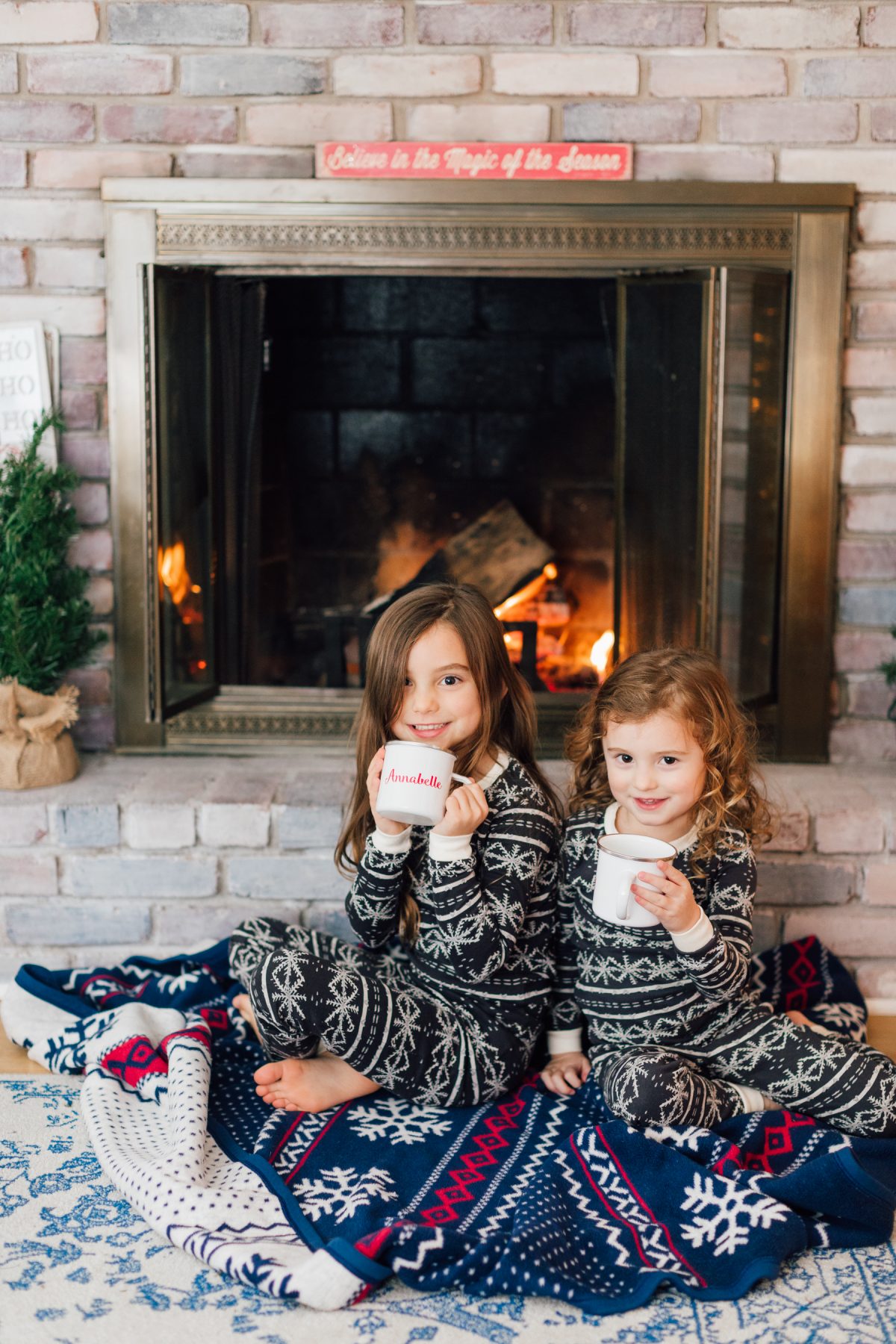Holiday Family Photo Inspiration - Little Girls Sipping Hot Cocoa by the Fireplace with Christmas Pajamas and Chappy Wrap Blanket