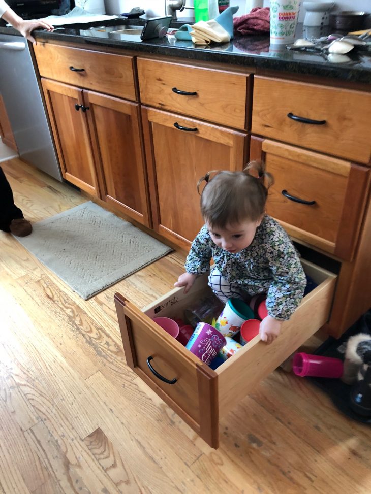 Child sitting in pull out drawer in kitchen