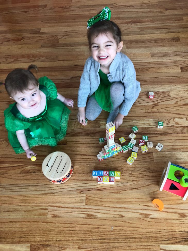 Little girls dressed in green playing with wood toys