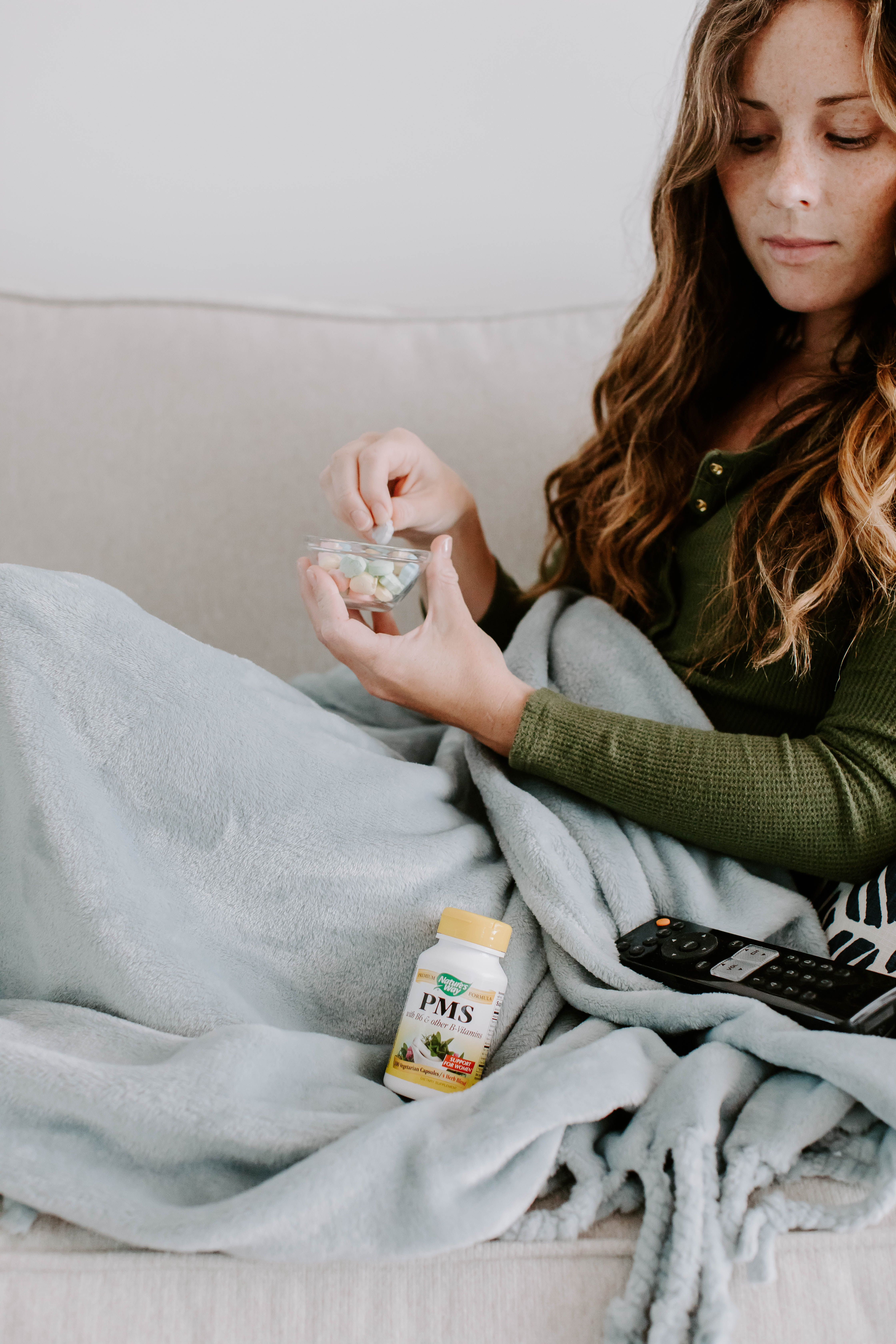 Woman eating candy on the couch with vitamins