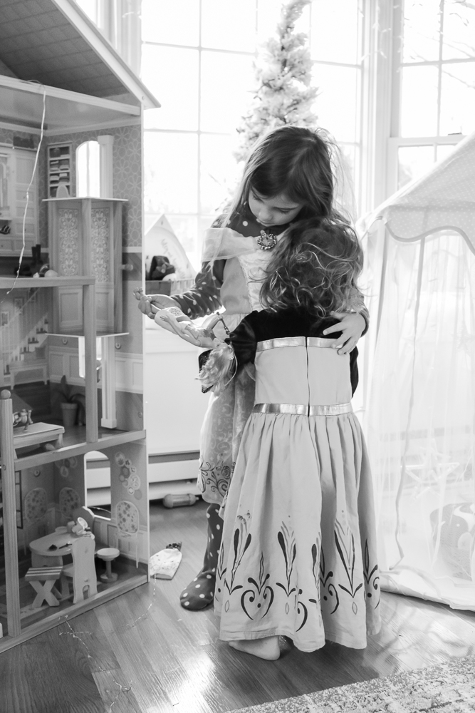 black and white photo of children hugging beside a large doll house