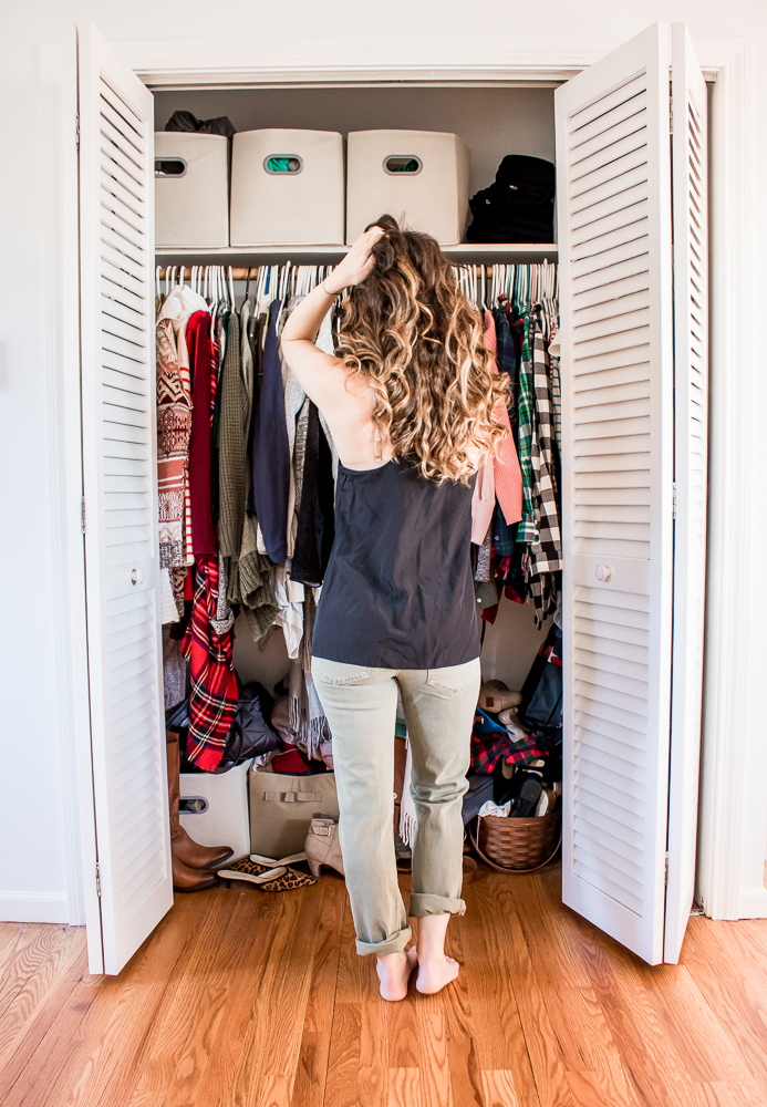 Woman scratching head in front of messy closet