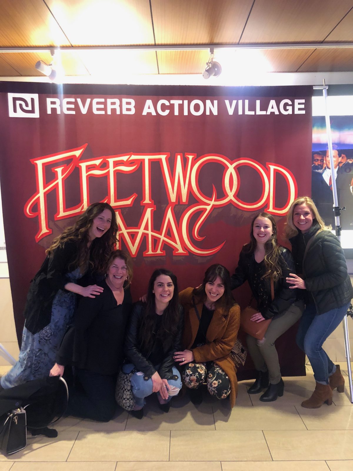 Women posing and laughing in front of Fleetwood Mac sign