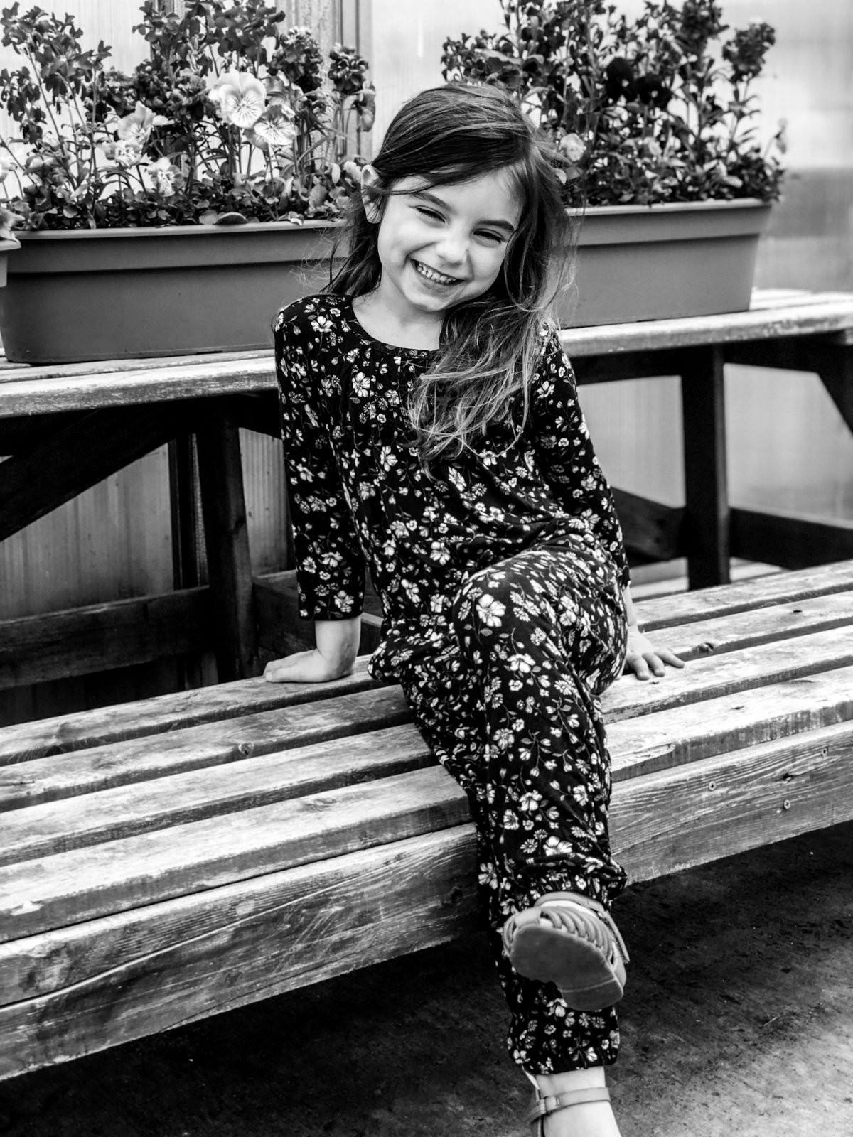 smiling little girl sitting on a bench in black and white