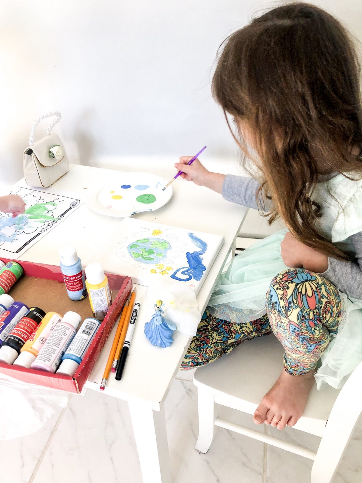 Little Girl painting a picture of the earth on a canvas 