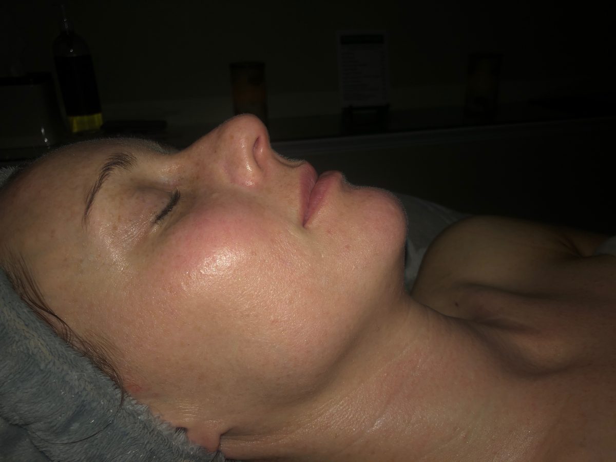 Woman's side profile, her eyes are closed and her skin is glowing from a facial at a spa 