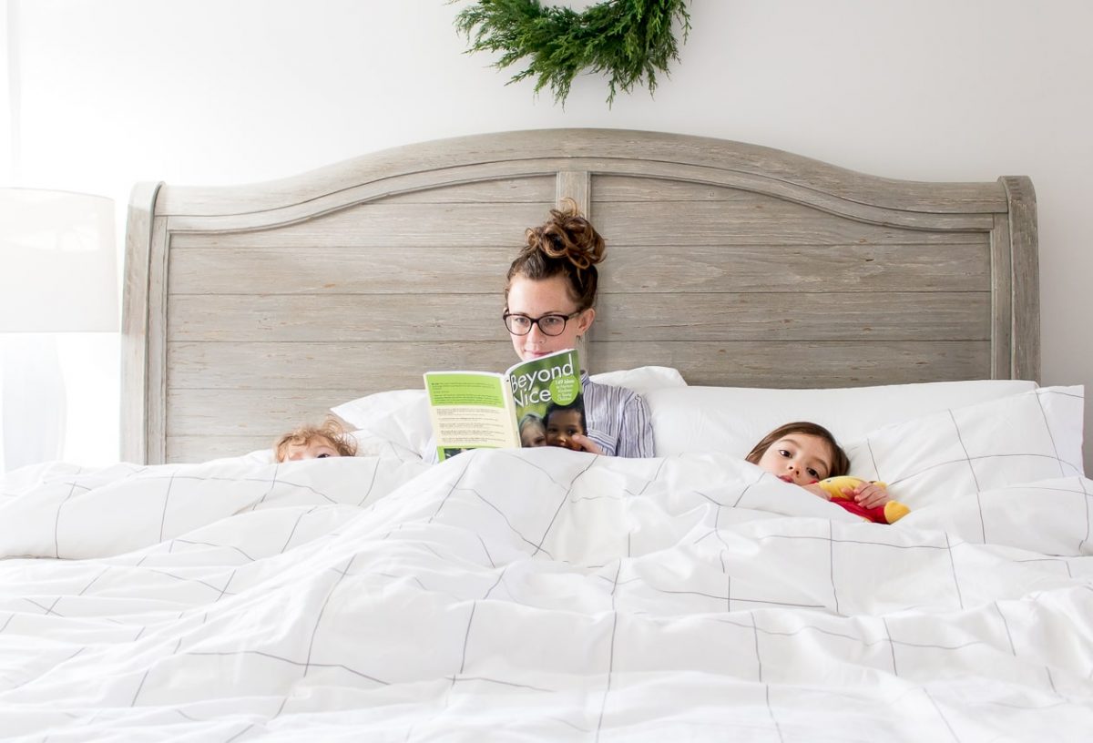 Mom in bed with little girls reading a book ready to sleep
