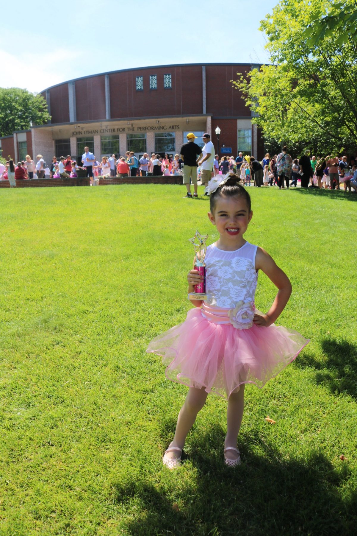 Ballerina after her dance recital holding trophy