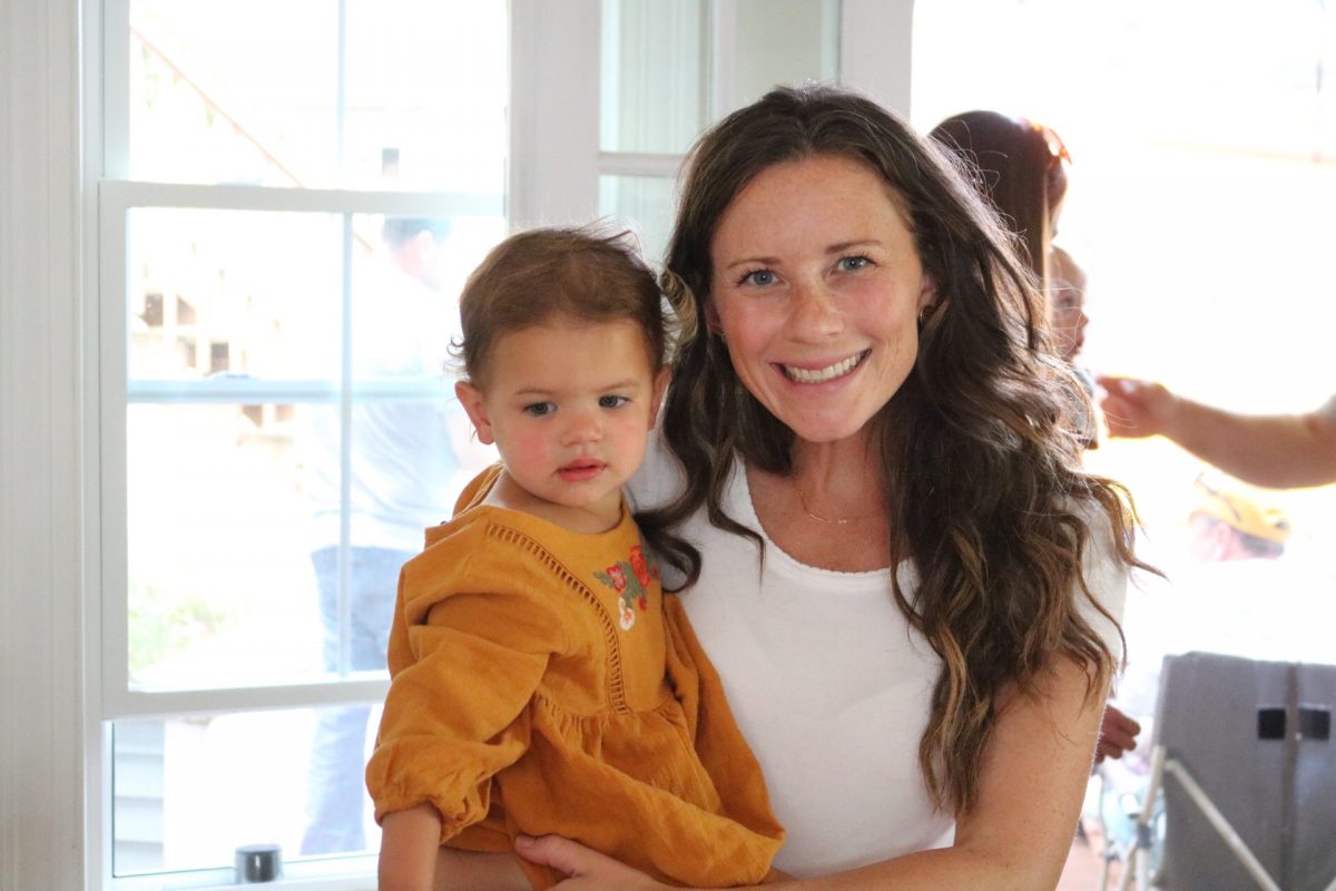 Woman in white shirt smiling and holding a little girl in a yellow dress