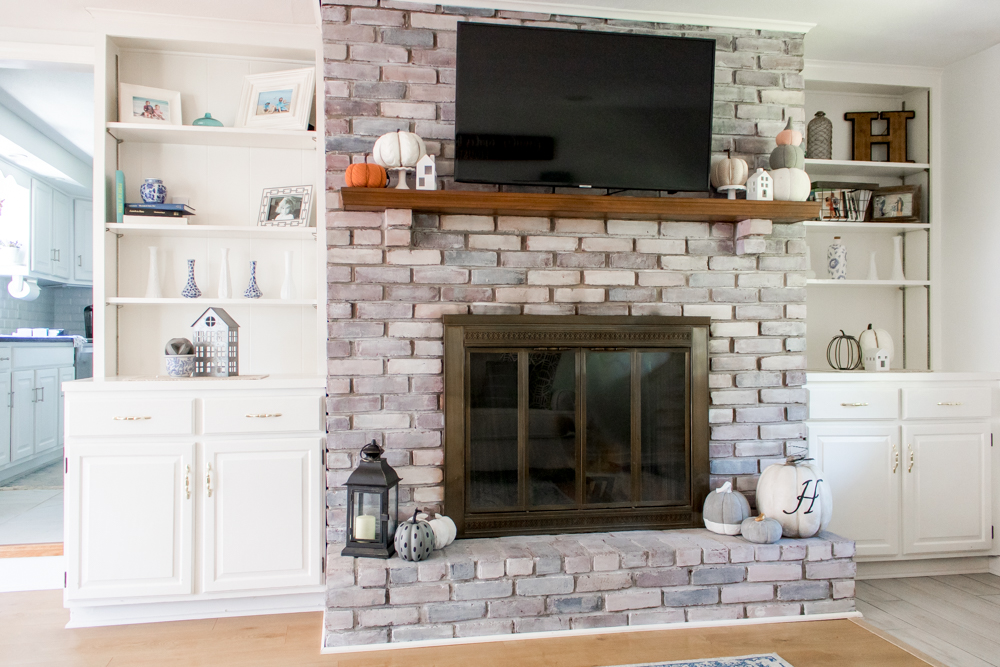 White Brick Fireplace Mantle and Built in Book Shelves Decorated for Fall with Neutral Colors