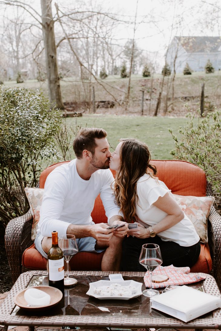 Man and Woman holding cards and kissing on outdoor couch