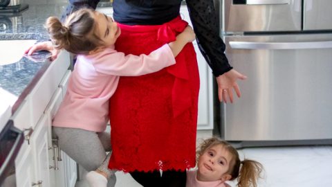 mom with towel in hair and date night outfit with kids hanging off of her