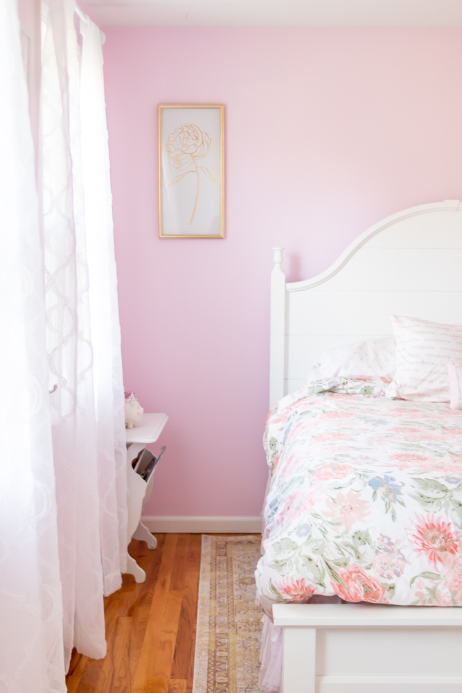 pink bedroom walls, white bed with floral bedding, white sheer curtains