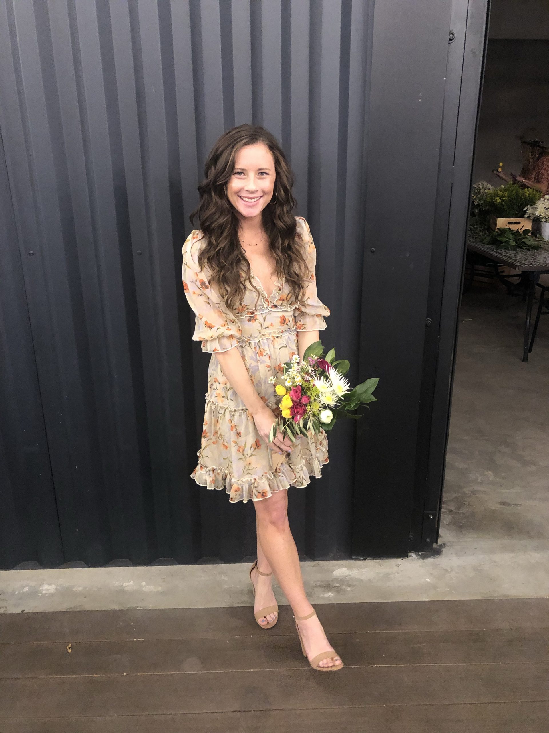 woman in tan floral dress holding bouquet