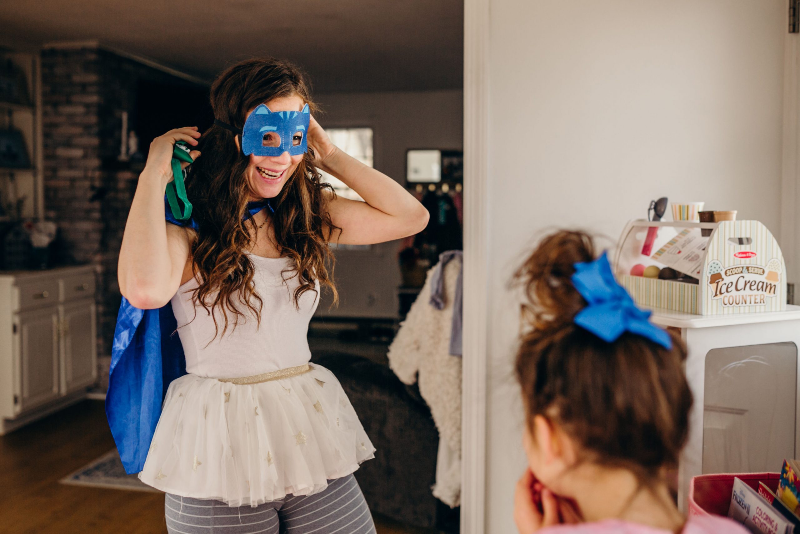 Mom wearing super hero mask and super hero cape with little girls