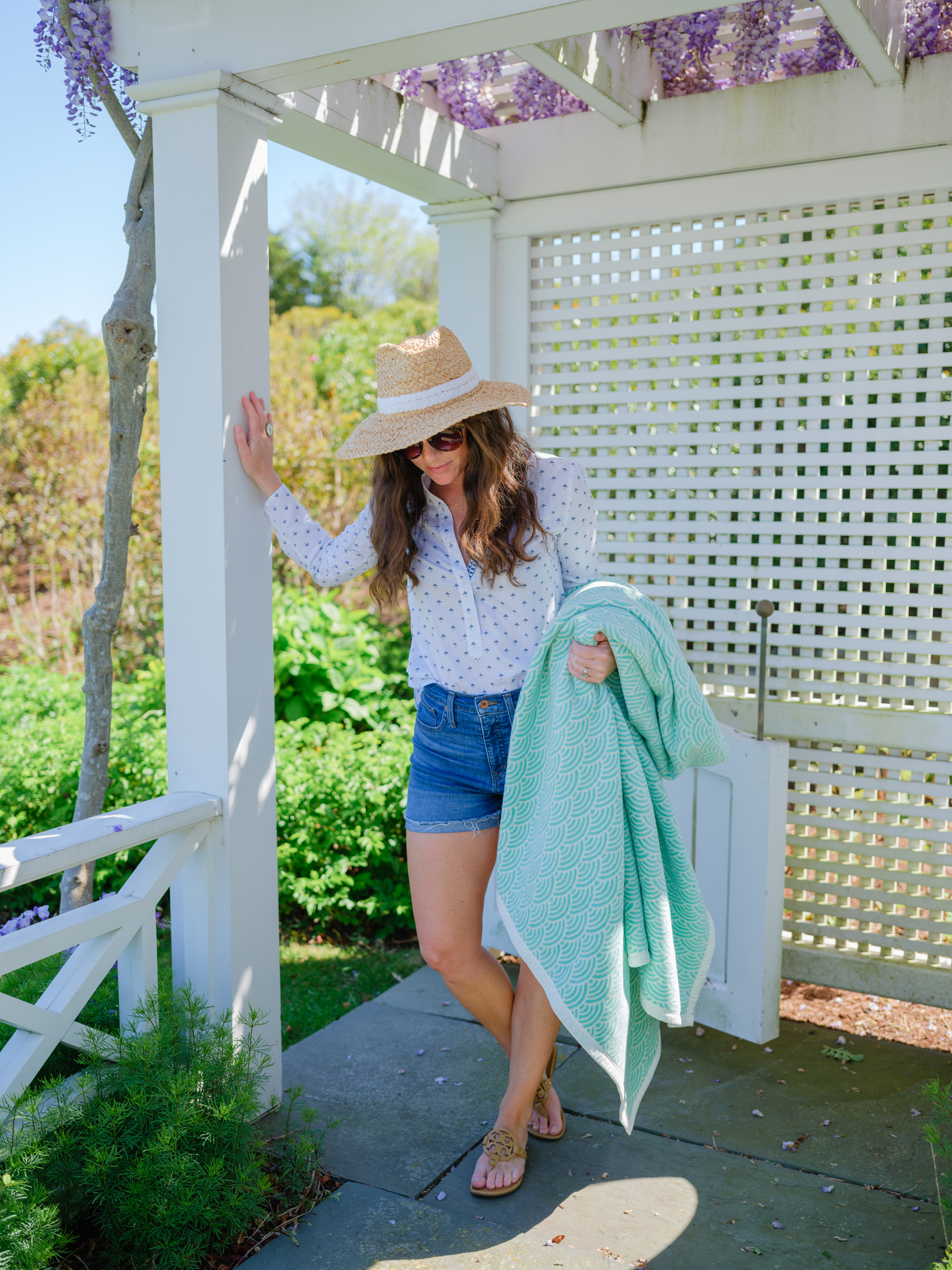 woman in summer hat shorts and chappy wrap blanket wisteria flowers