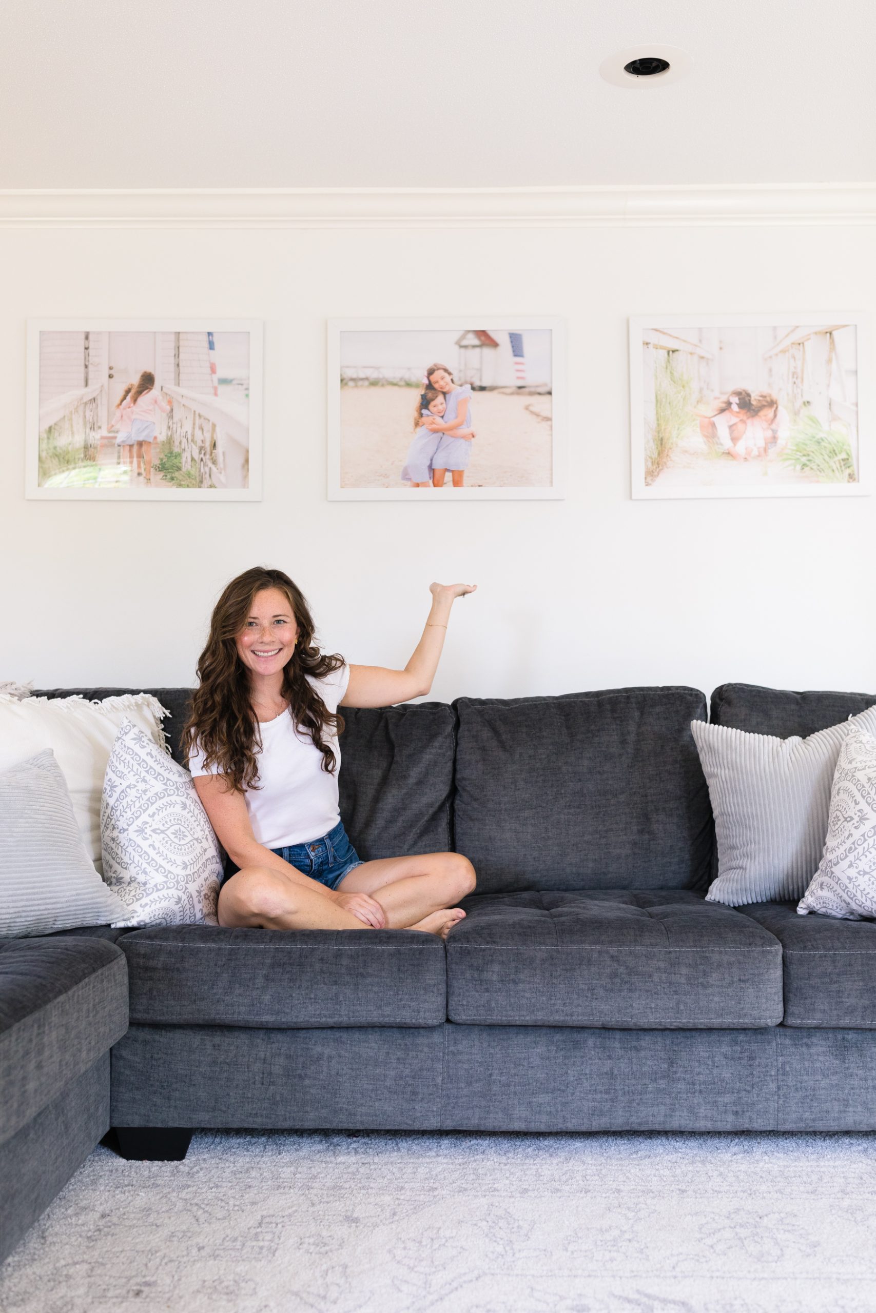 woman sitting on couch with enlarged prints hanging on the wall above sofa