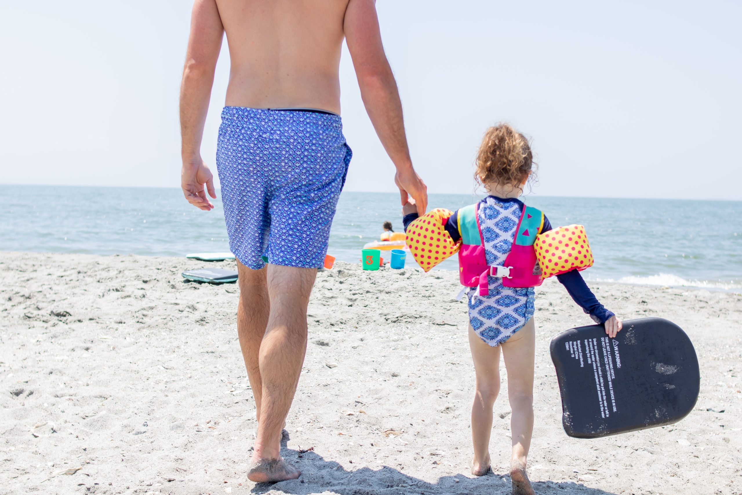 Dad and Daughter walking on the beach in July in matching swimsuits