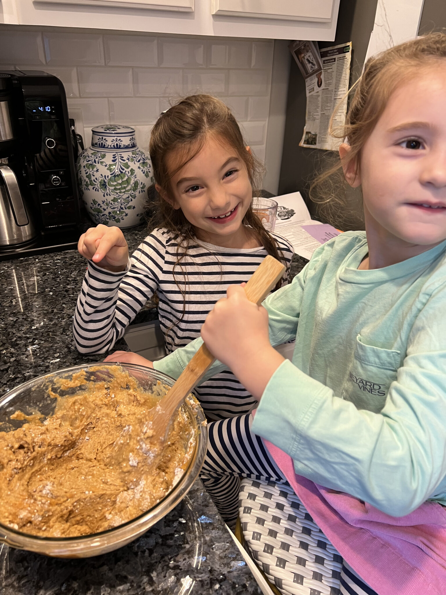 Little girls mixing pumpkin muffin mix in kitchen