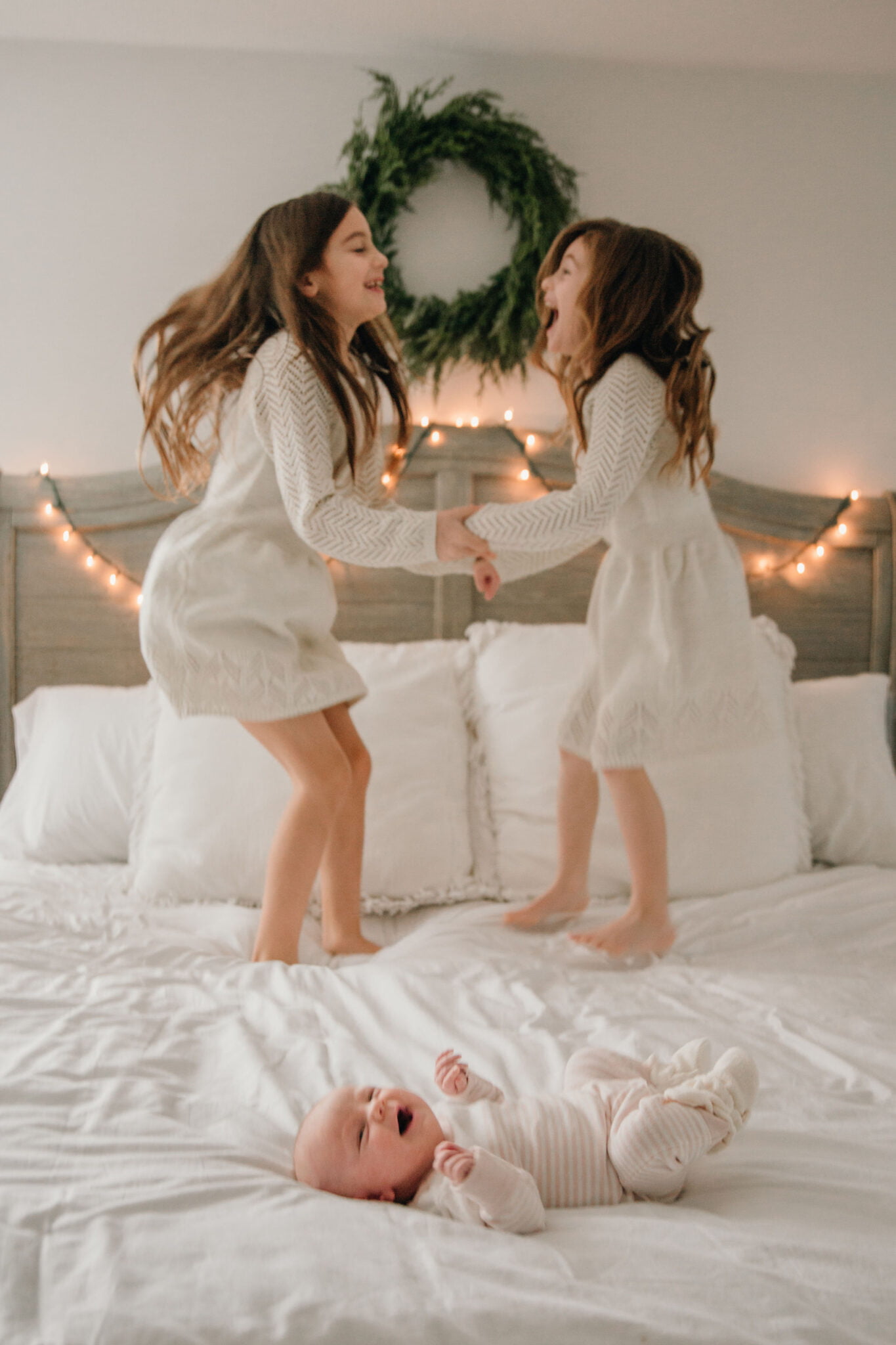 Parents of 3 kids - big sisters jumping on bed with baby sister