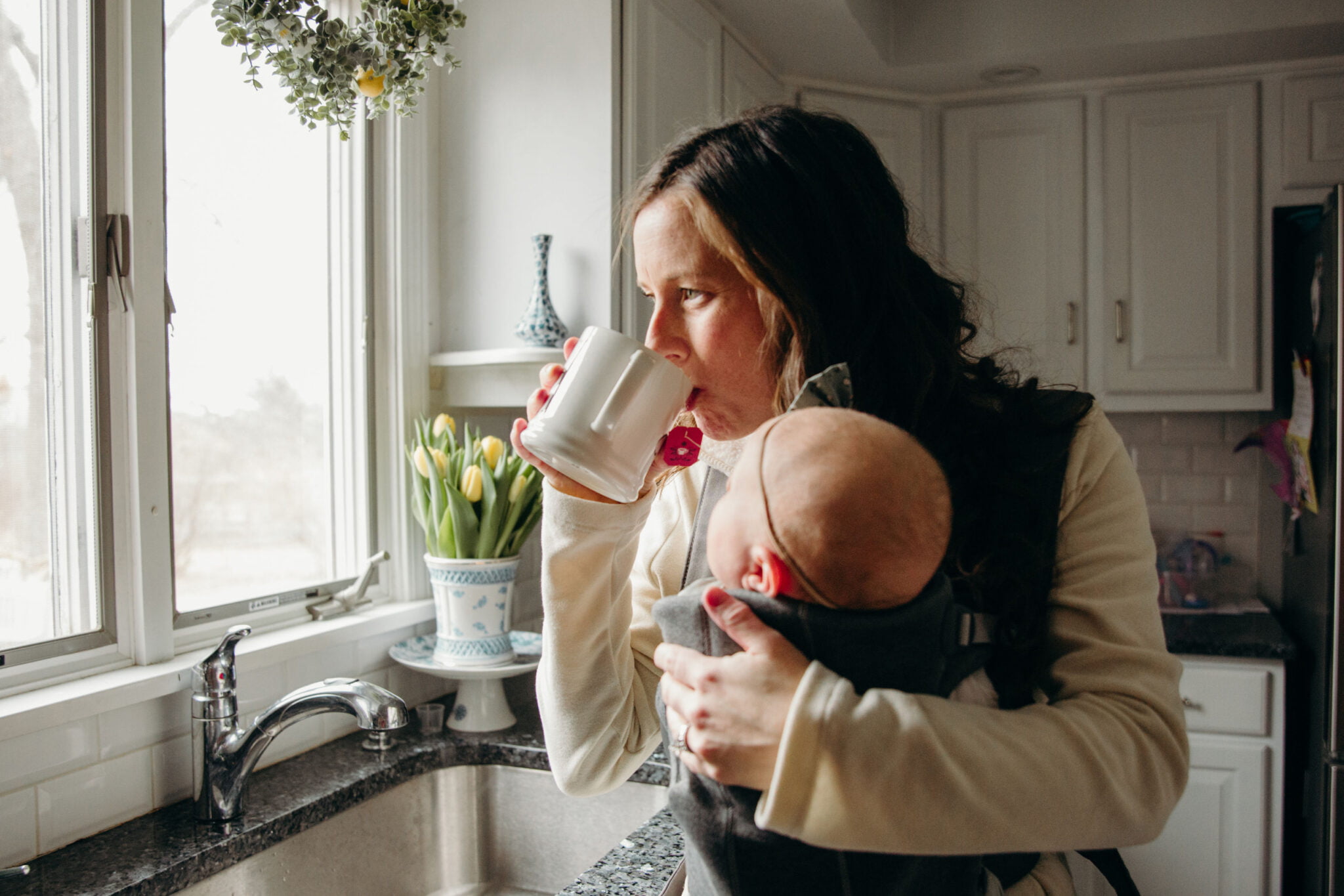 mom sipping coffee while holding baby