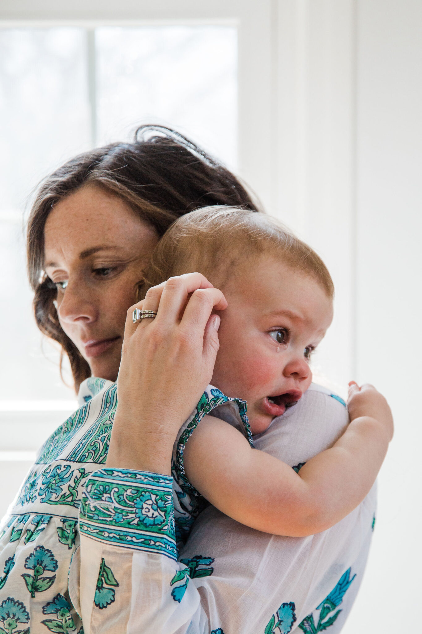 Mom holding sad baby wearing personalized jewelry warren birthstone ring
