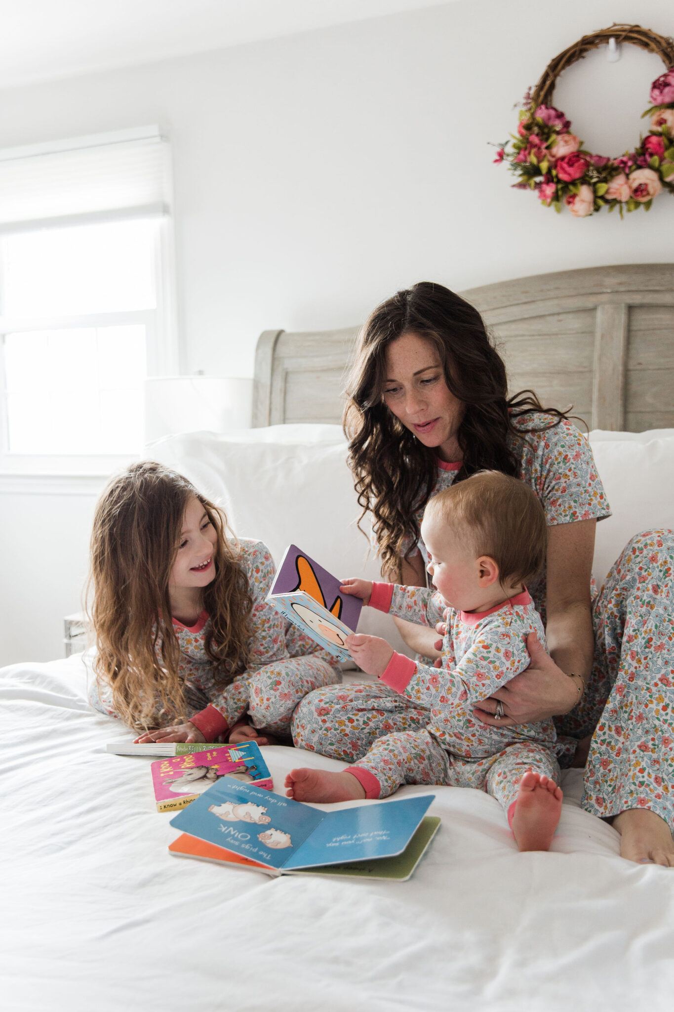 Mom and daughters in matching Lake pajamas reading books in bed