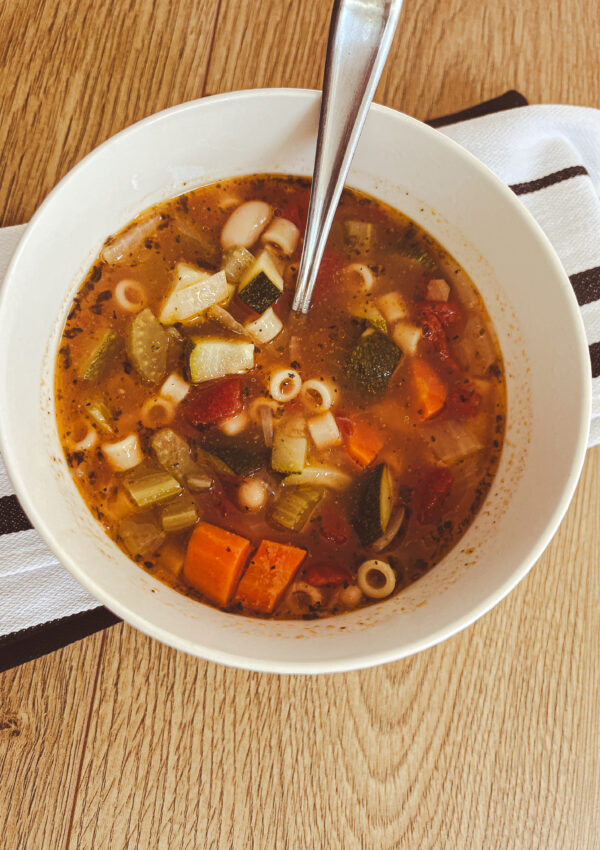 white bowl with spoon chunky minestrone soup zucchini ditalini tomato carrot