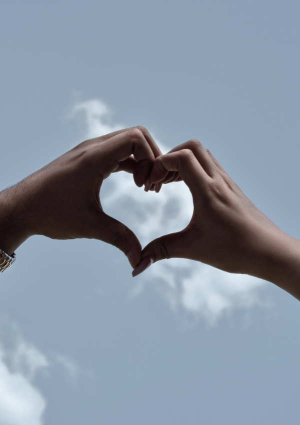 hands making heart shape with clouds in background