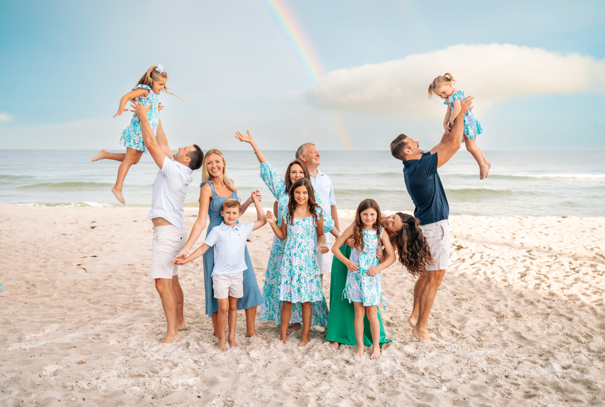 large family photo at beach dads tossing toddlers in air