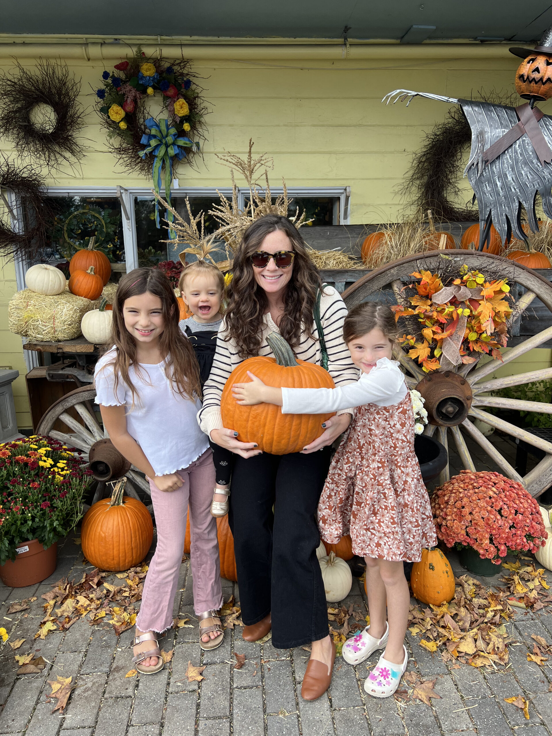 woman holding giant pumpkin standing with three daughters fall in Connecticut