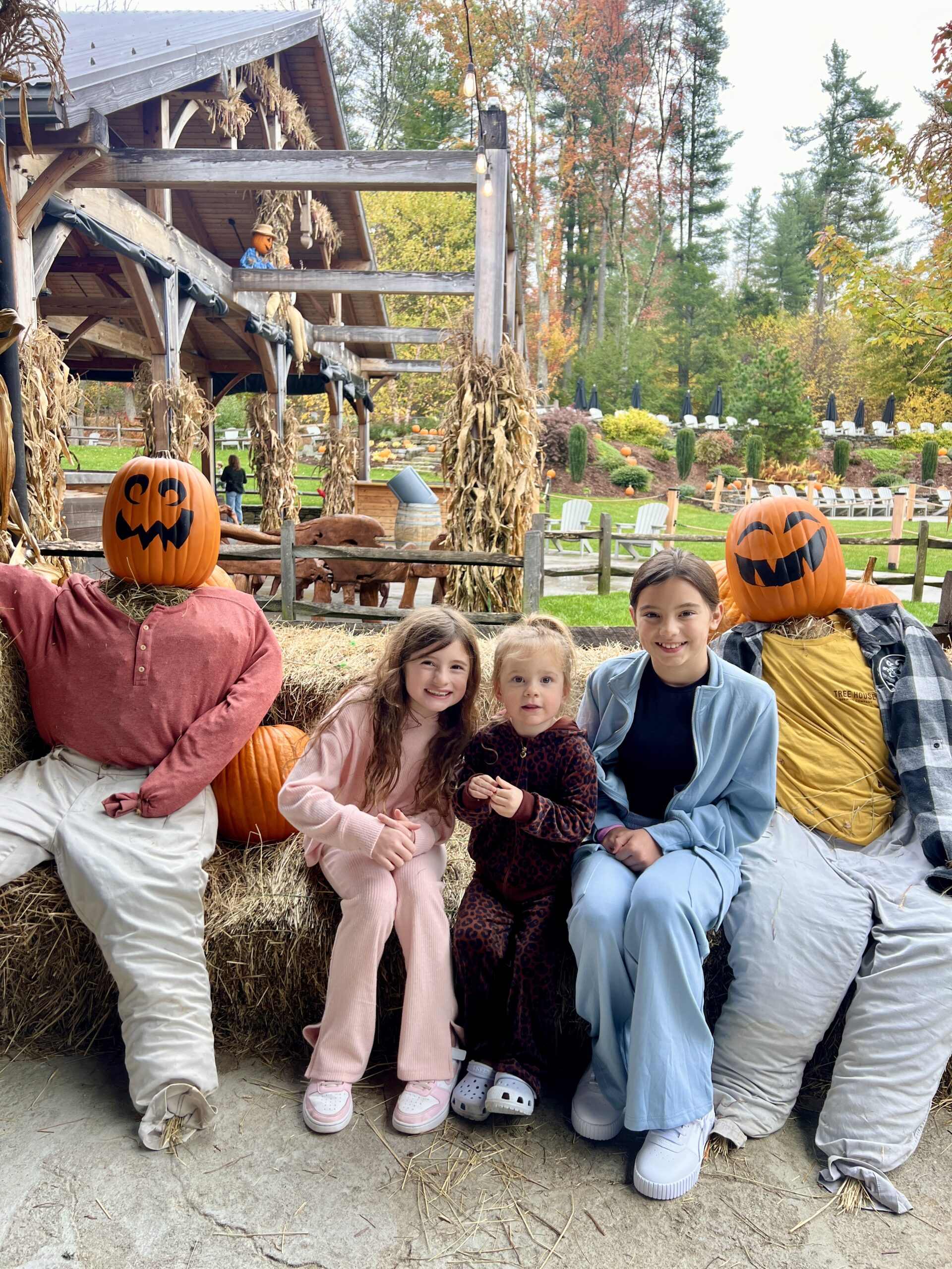 Three girls sitting with pumpkin head scarecrows Connecticut Bucket List