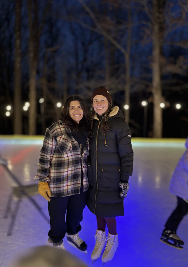Girl friends on ice skates on backyard skating rink