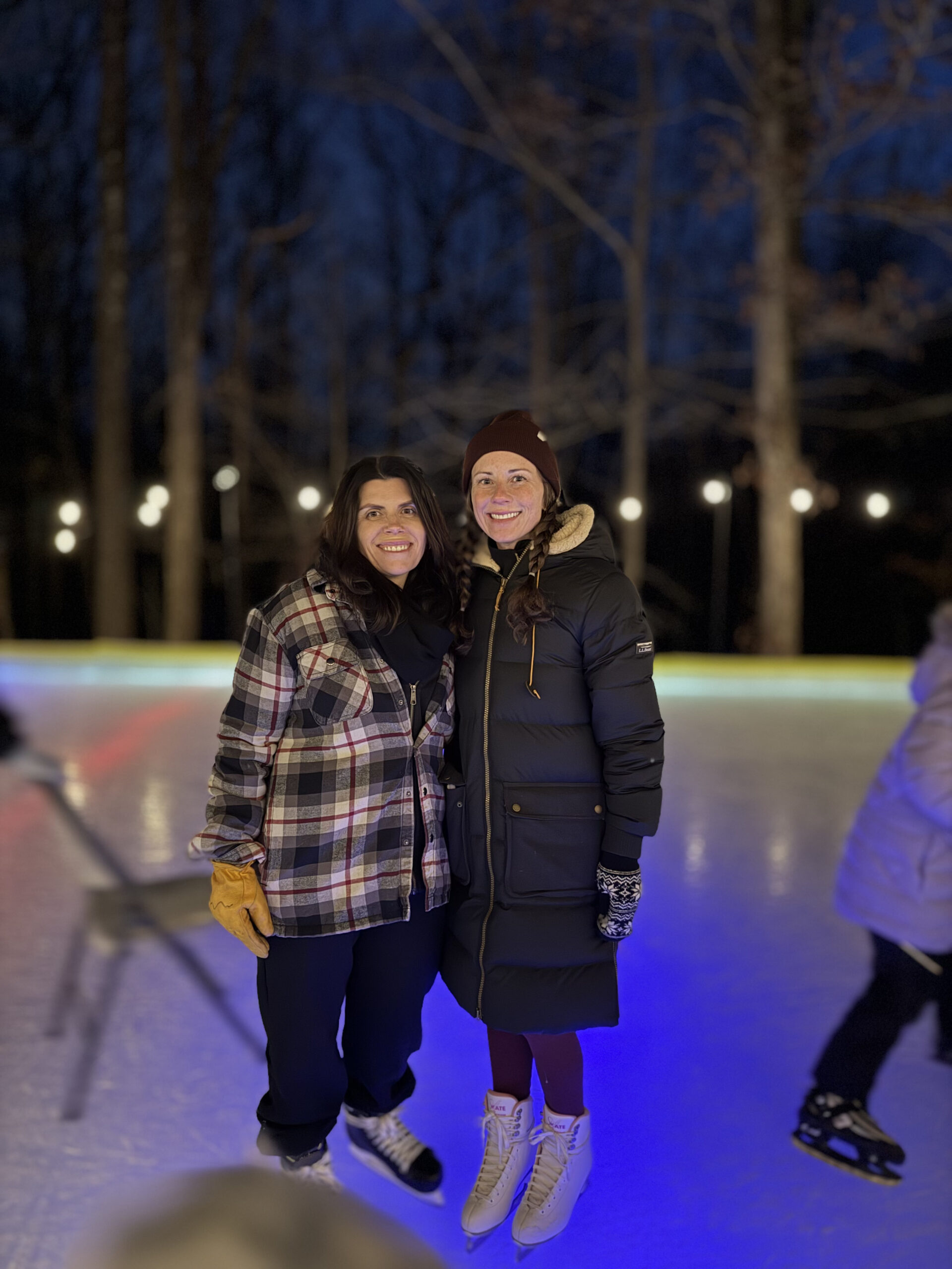 Girl friends on ice skates on backyard skating rink