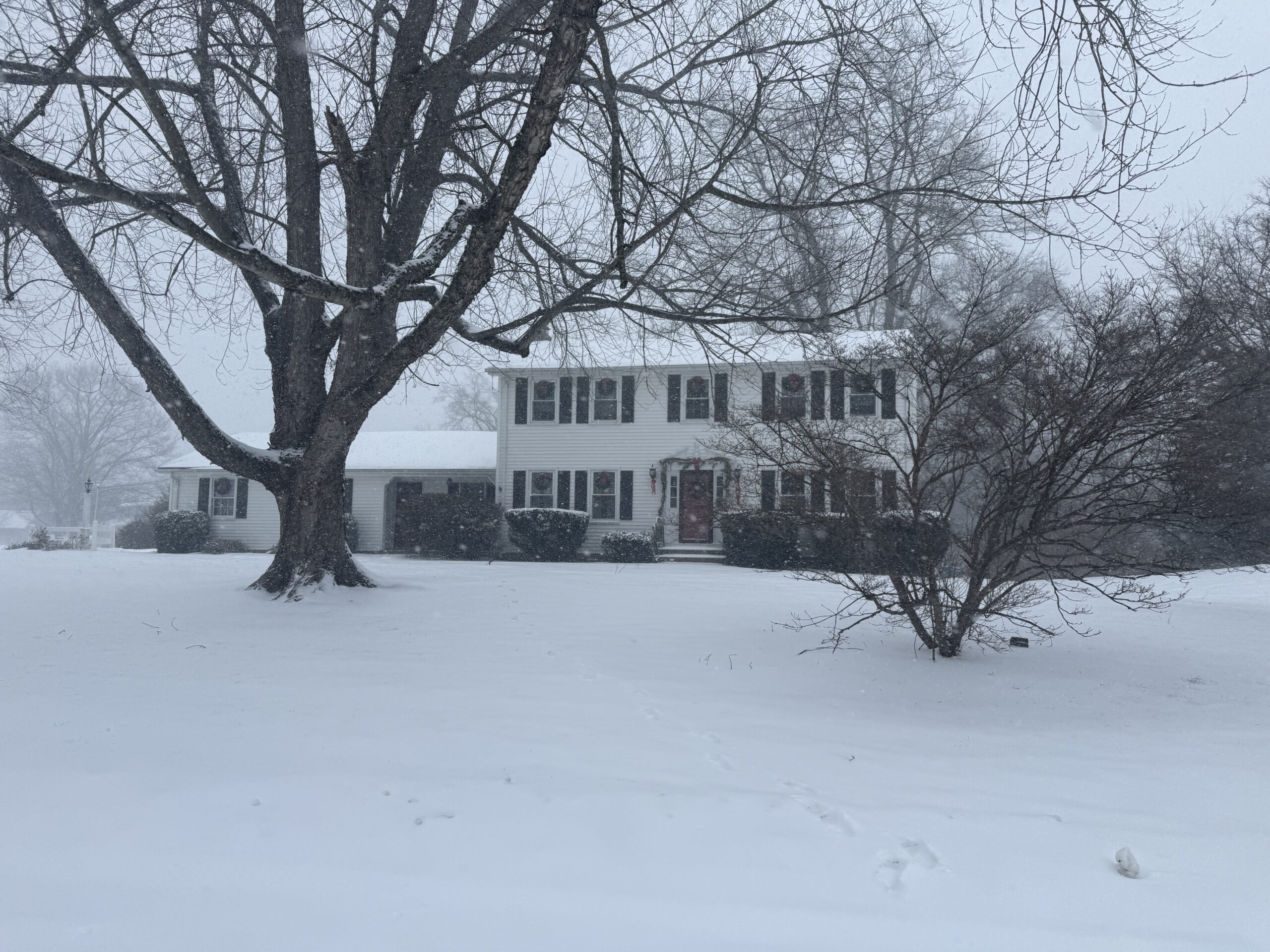 snowy photo of white colonial home