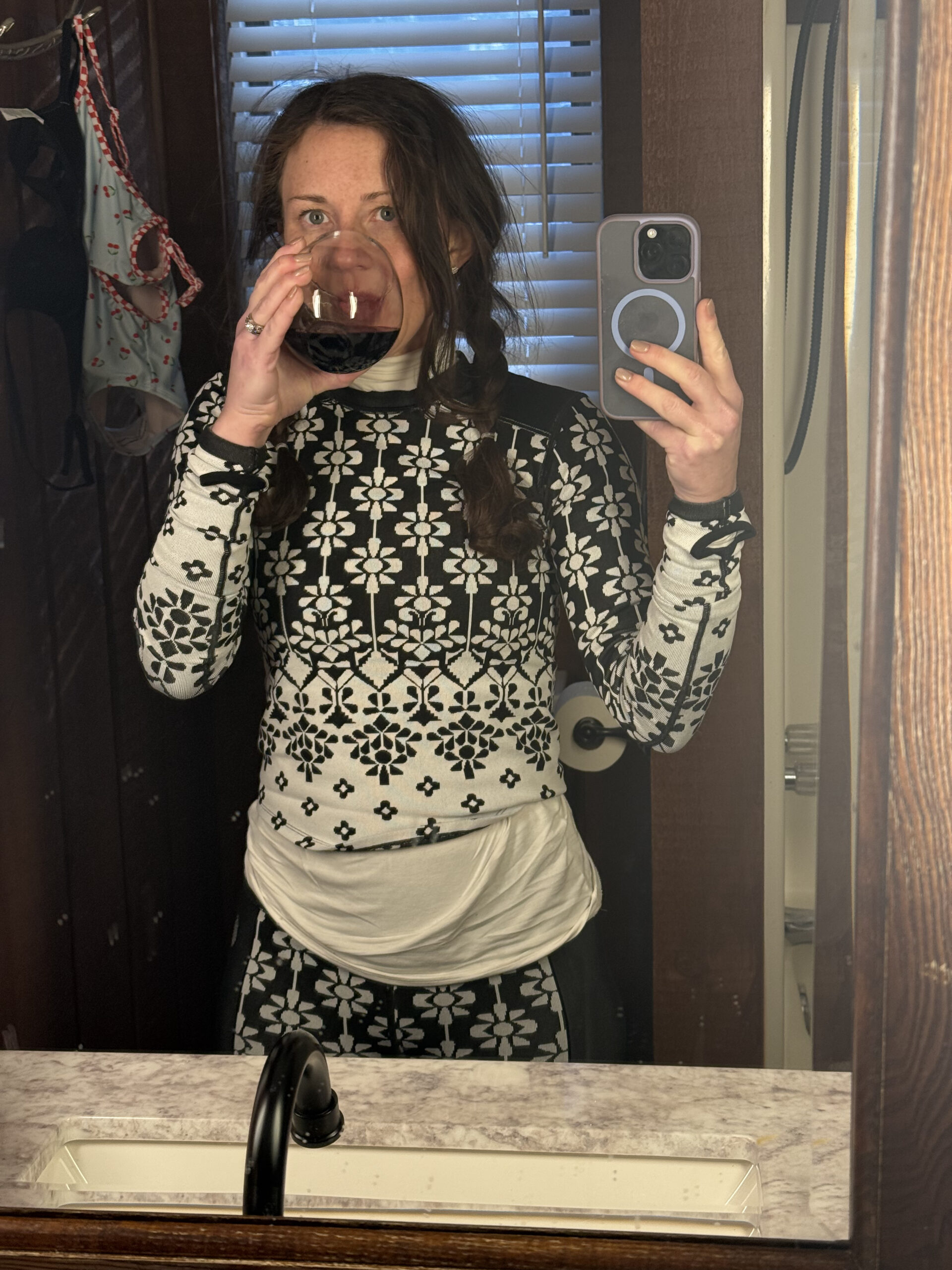 woman in ski base layer set with messy hair drinking wine 
