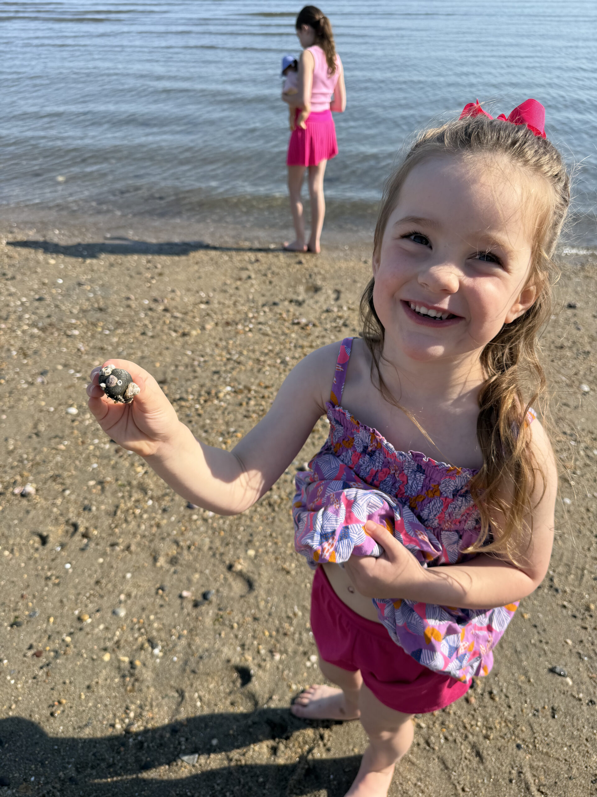 toddler on beach in May holding a seashell
