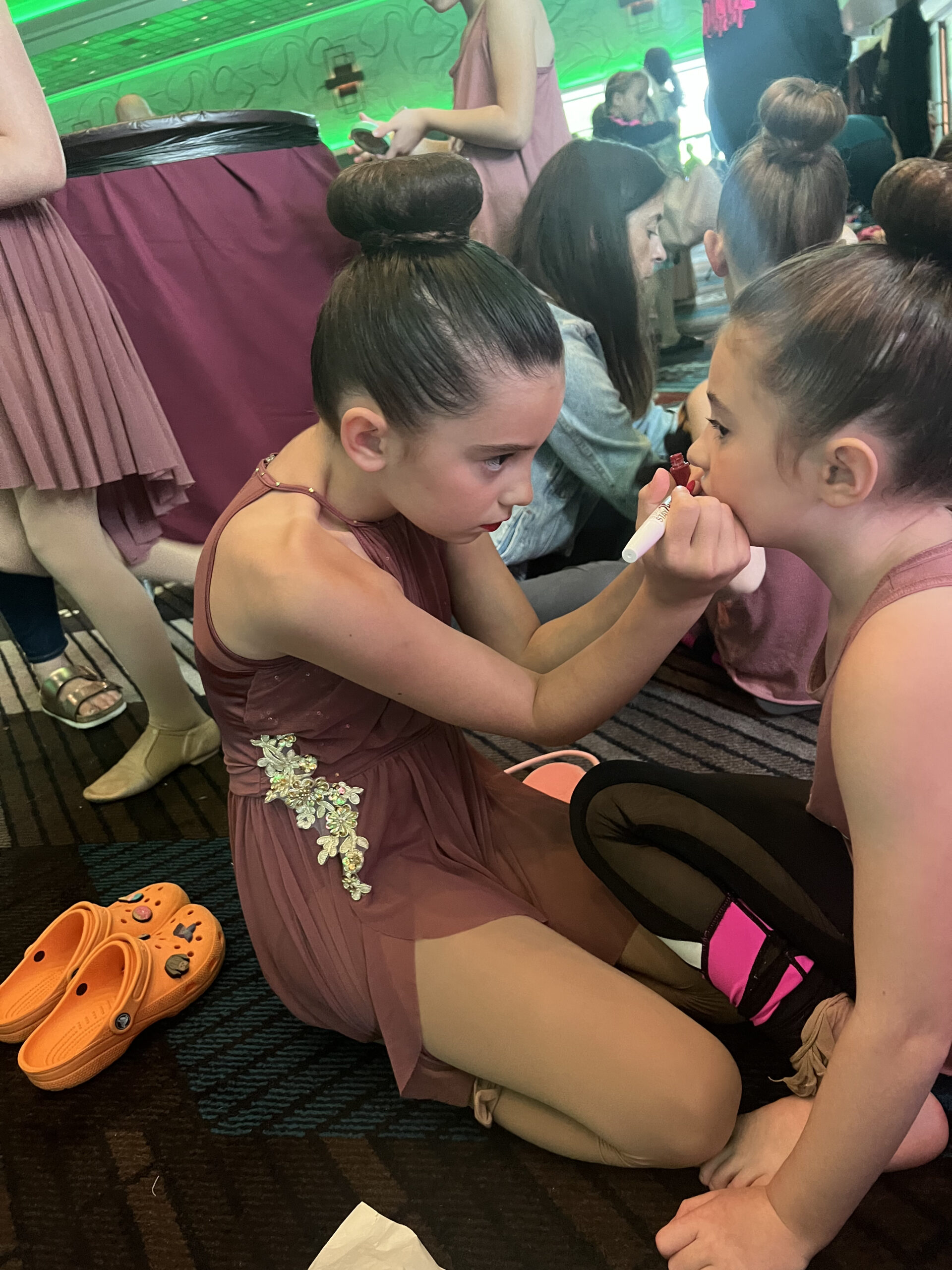 dancers applying red lip stain at dance competition