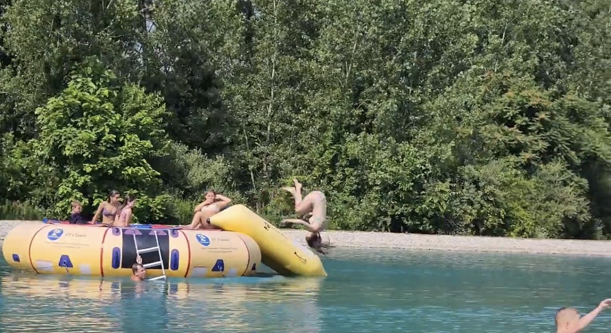 Mom doing a front flip off a pond trampoline during a summer family adventure