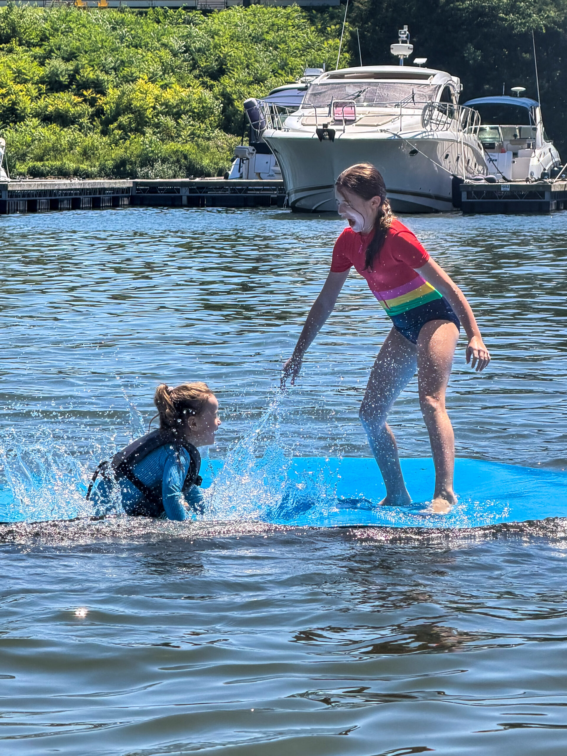 sisters playing on water lily pad splashing having summer fun