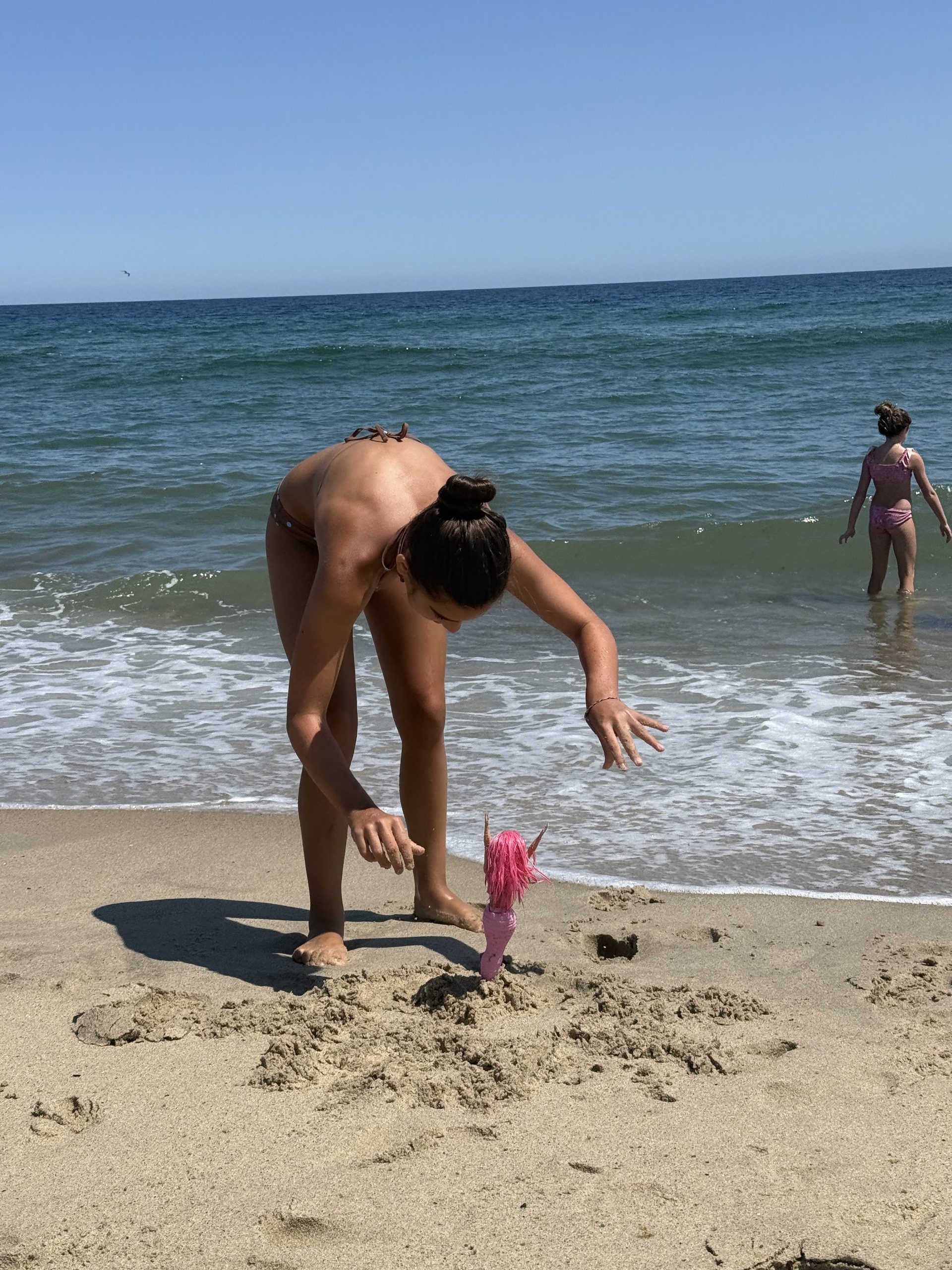 Little girl playing with barbie at beach in Cape Cod