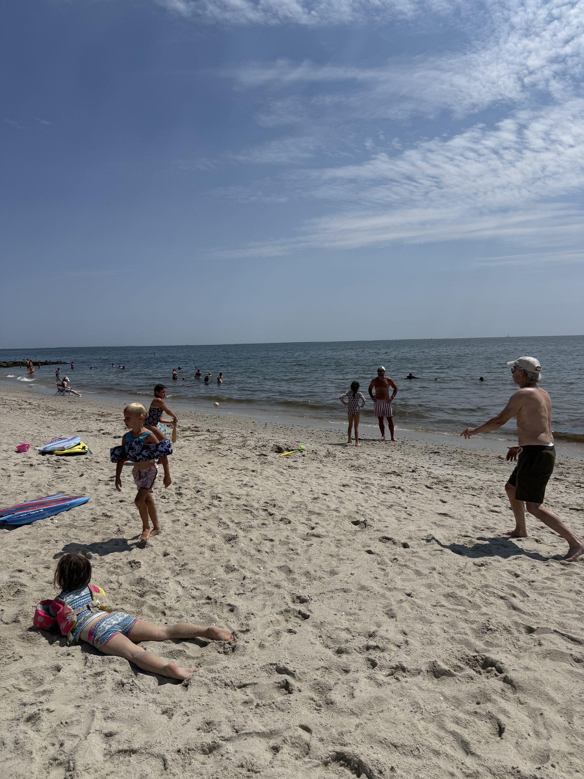 Grandpa pitching softball to kids on beach in Cape Cod